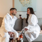 Couple en peignoir avec bouteille de vin à la chambre d'hôtel.